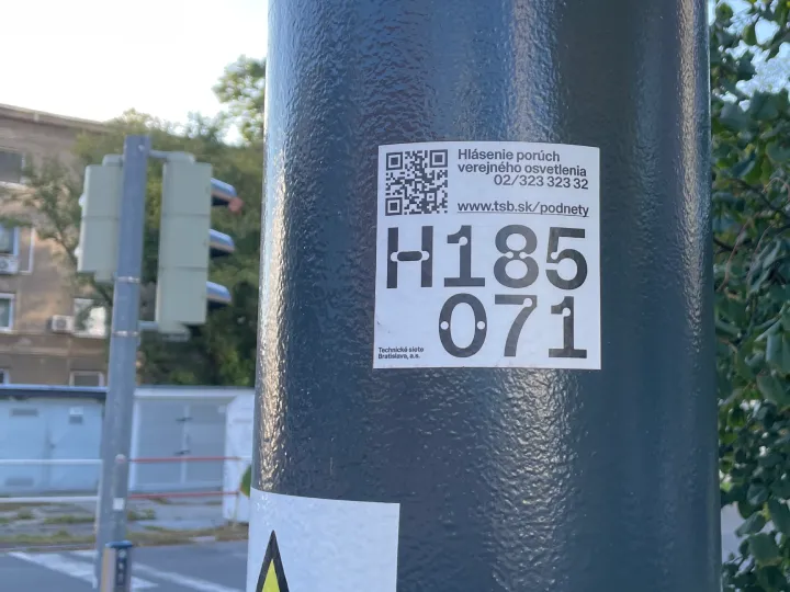 Photo of a street light pole in Bratislava. The QR code opens a form for reporting errors.